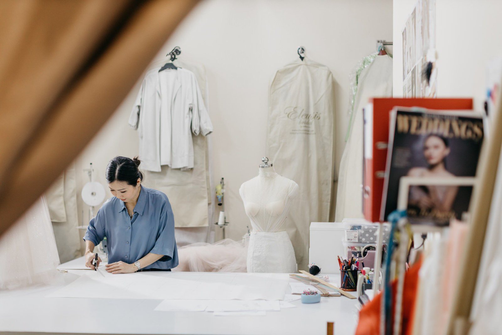 A behind the scenes photo of Celine Ooi meticulously working on a bridal gown during the video shoot. by cliff choong