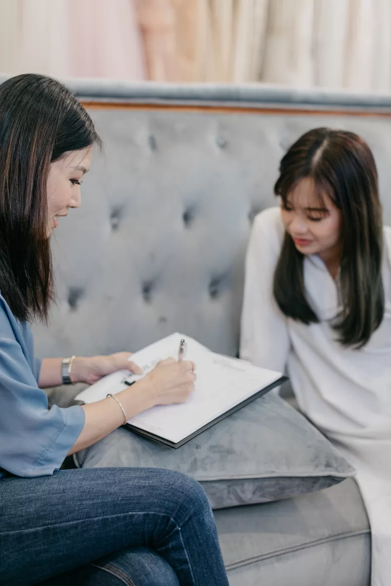 A behind the scenes photo of Celine Ooi meticulously working on a bridal gown during the video shoot. by cliff choong