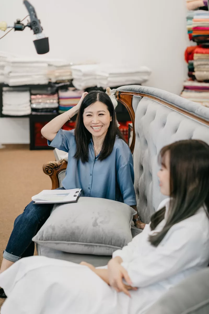 A behind the scenes photo of Celine Ooi meticulously working on a bridal gown during the video shoot. by cliff choong